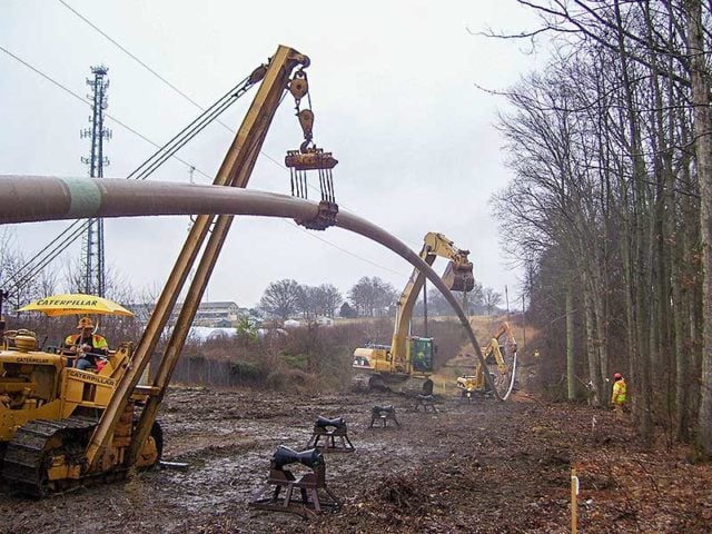 A crane hoists a pipe used in trenchless technology applications.