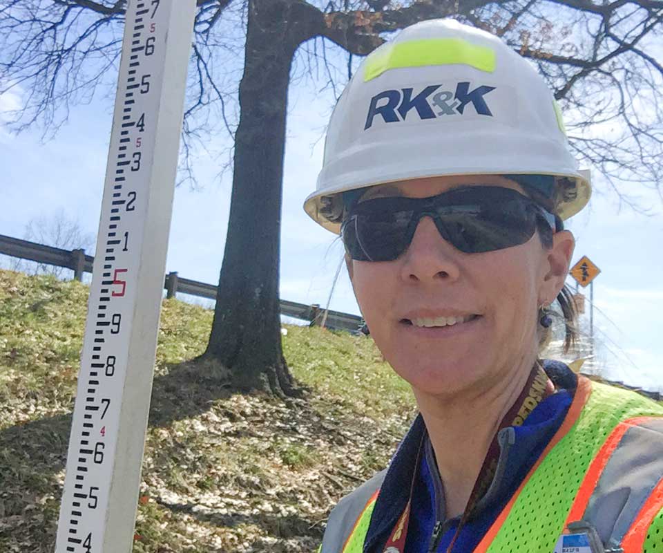 Kathy standing in the field wearing a hard hat