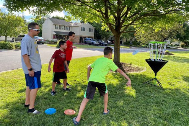 Josh Golomb and his three sons playing disc golf.