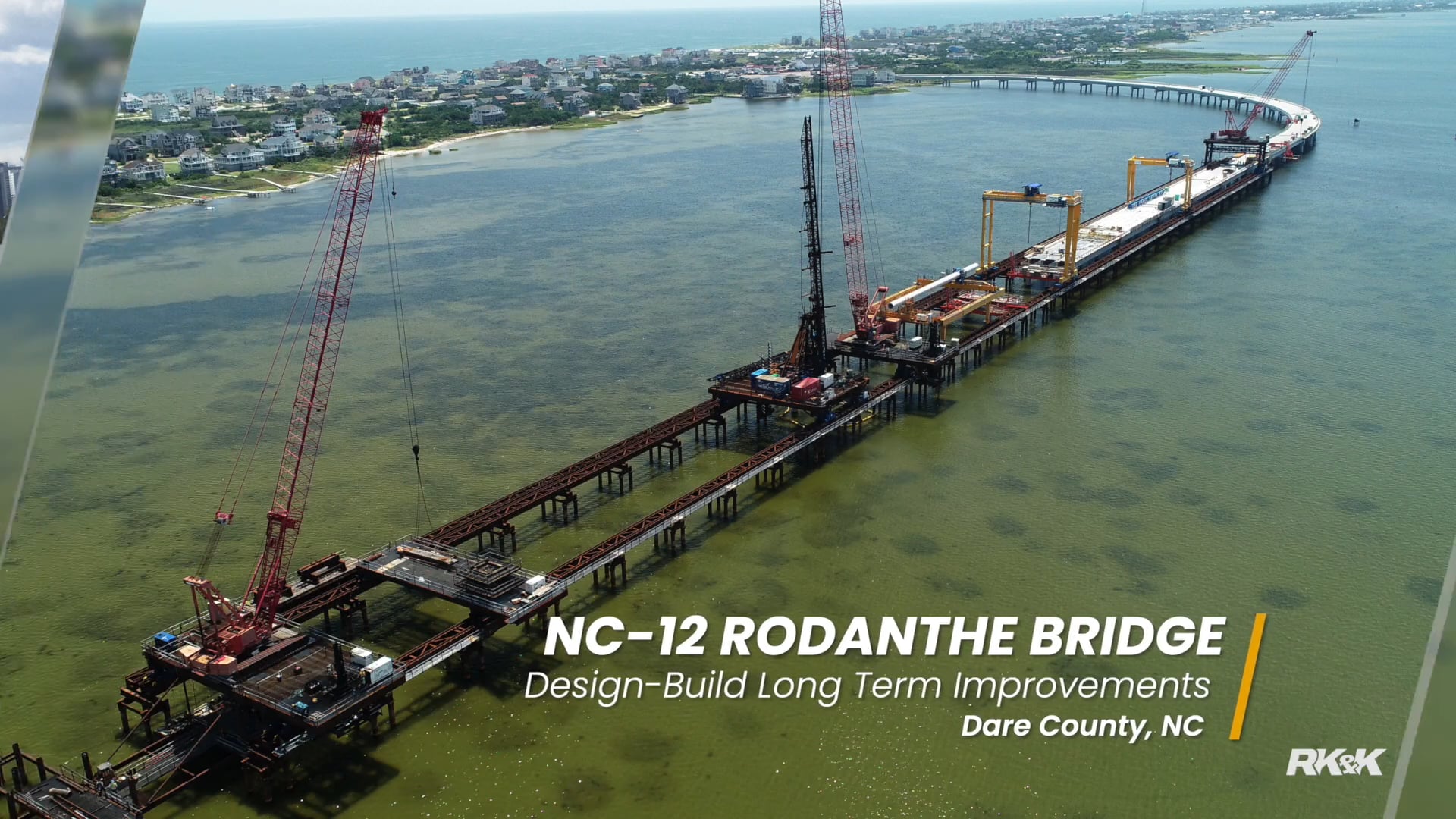 Aerial view of the NC‑12 Rodanthe Bridge under construction with cranes and work platforms extending across coastal waters in Dare County, NC.