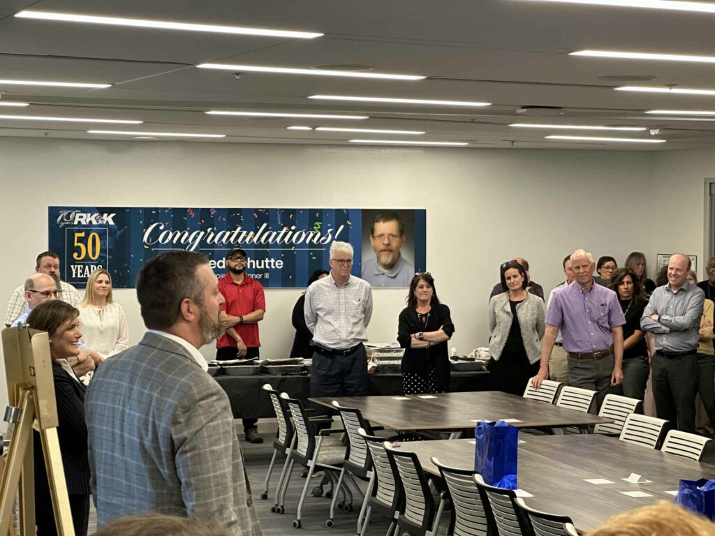 Employees of RK&K and a sign congratulating Fred Schutte on 50 years of work