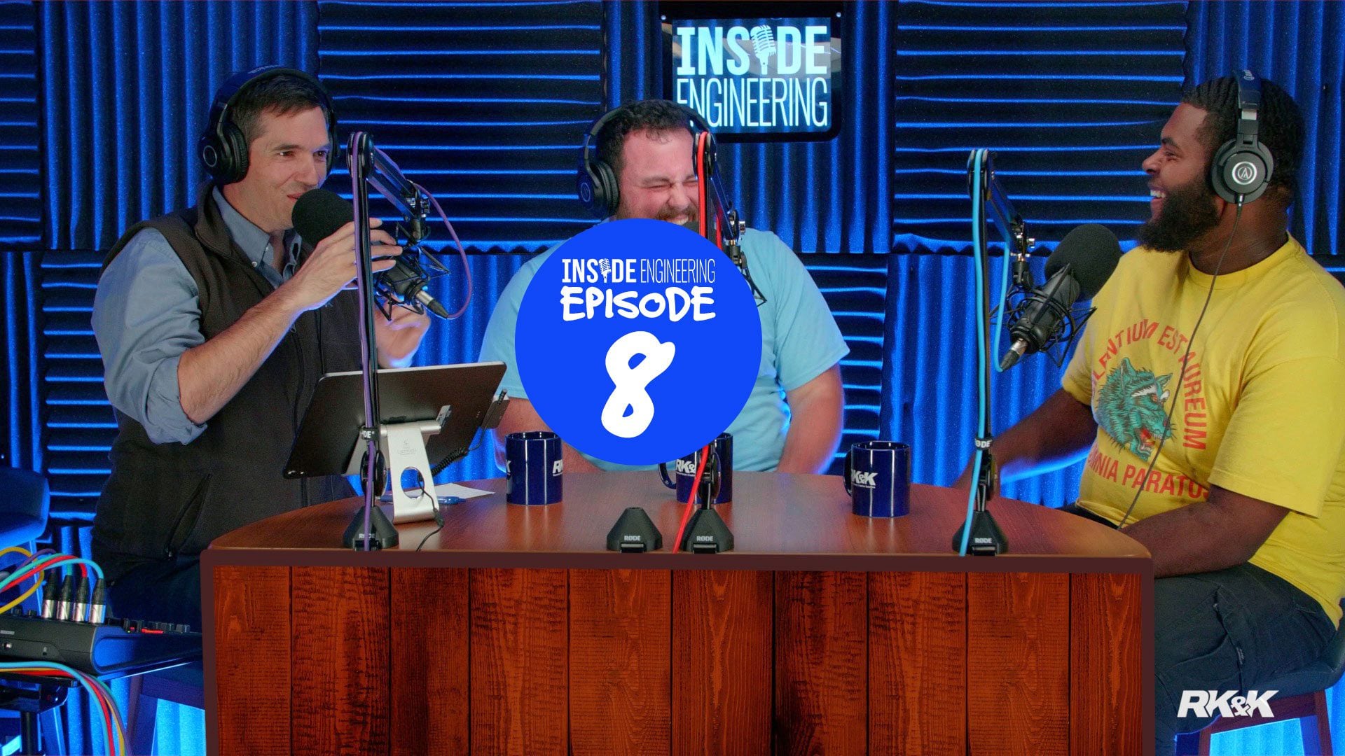 Podcast studio with three people seated at a table, microphones, and text overlay reading “Episode 8.”