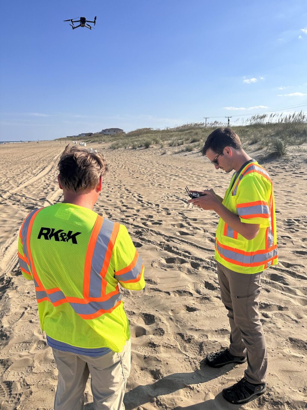 Two men on a beach operating a drone.