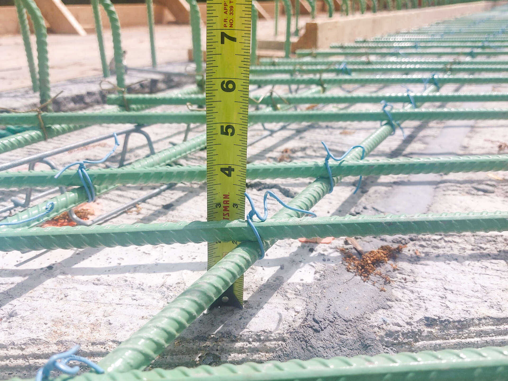 Close-up of epoxy-coated rebar grid on the Henryton Road Bridge with a tape measure showing proper spacing prior to concrete placement.