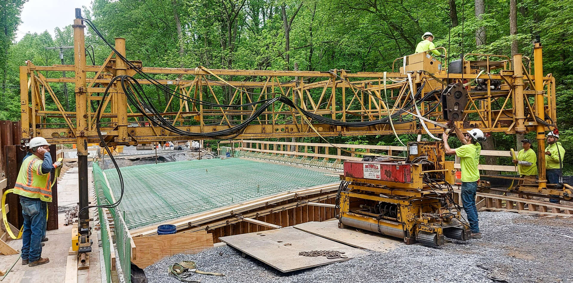 New Henryton Road bridge spanning a shallow, rocky stream, showing the completed concrete structure in a wooded setting.