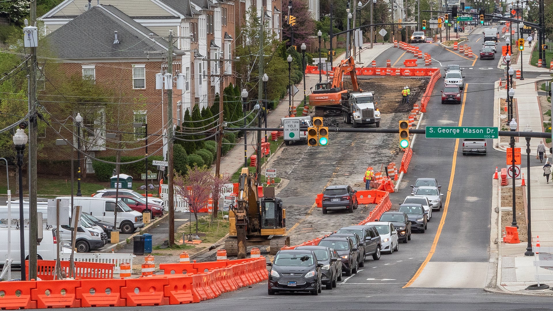 Construction underway on a multimodal transportation corridor, with traffic maintained alongside a work zone where roadway and streetscape improvements are being installed.
