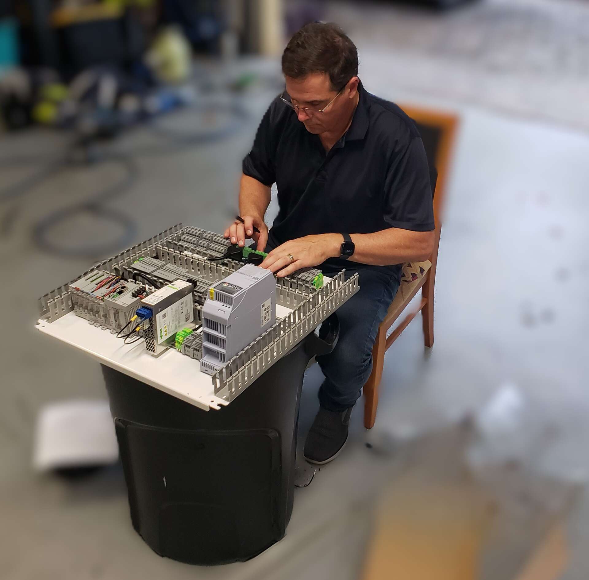 Technician building and testing a PLC control panel for a SCADA system.